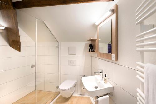 a white bathroom with a sink and a toilet at KONCEPT HOTEL Löie in Münsingen