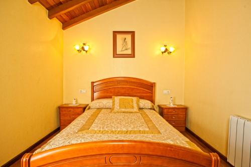 um quarto com uma cama de madeira e duas mesas de cabeceira em Casa Marcelino em Muxía