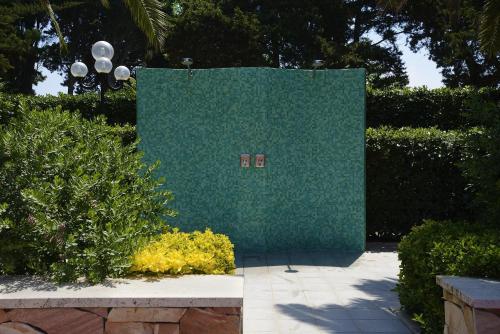 a green wall with two signs on it in a garden at Hotel Oasis in Alghero