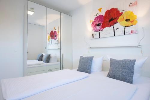 1 dormitorio con 2 camas blancas y espejo en Badeweg 4 Sandkorn 2, en Scharbeutz