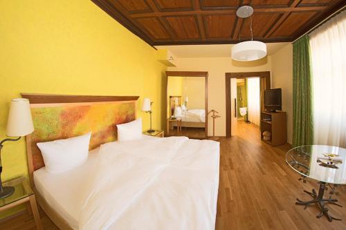 a bedroom with a large white bed and a television at Trip Inn Hotel Der Adelshof in Schwäbisch Hall
