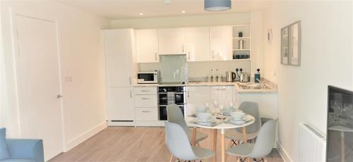 a white kitchen with a small table and chairs at Sea Breeze, gorgeous 2 bed apartment in Exmouth in Exmouth