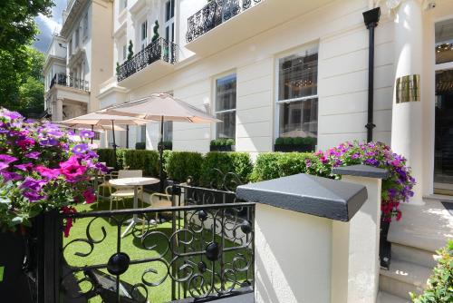 倫敦的住宿－倫敦尊貴帕丁頓海德公園酒店，大楼前带桌子和鲜花的阳台