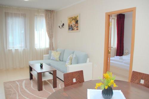 a living room with a blue couch and a table at Гранд Манастира Апартаменти "Зимна приказка" in Pamporovo