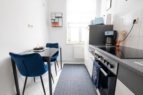 een kleine keuken met een tafel en een blauwe stoel bij Tiny Home in schickem Jugendstilviertel in Chemnitz