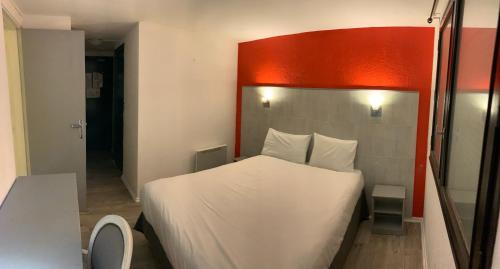 a bedroom with a white bed with a red headboard at Hôtel Le Forestia in Pannes