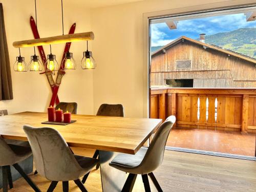 ein Esszimmer mit einem Tisch und Stühlen sowie einem großen Fenster in der Unterkunft Tiroler Zeitgeist Apartment Fügen in Fügen