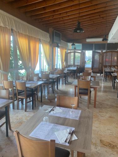 un restaurante con mesas y sillas de madera y ventanas en Hostal El Perejil en Cuevas del Almanzora