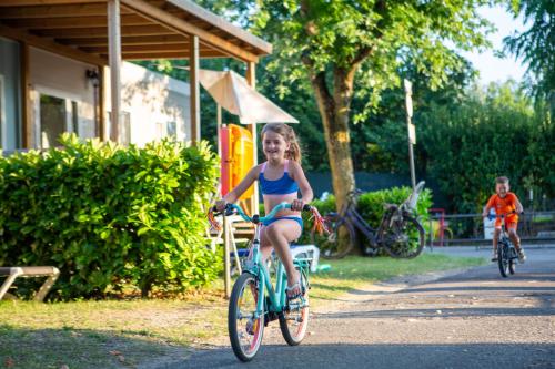 a little girl riding a bike down a street at Camping Del Sole Village in Iseo