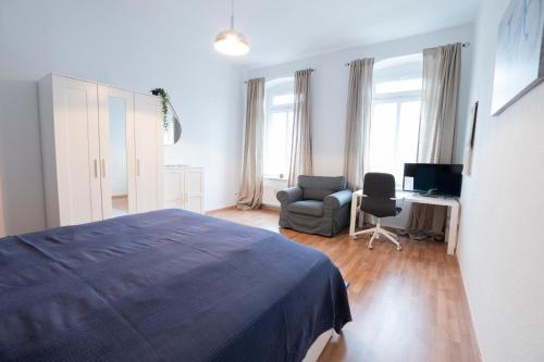ein Schlafzimmer mit einem Bett, einem Stuhl und einem Schreibtisch in der Unterkunft Lutherviertel-Apartment mit 2 SZ in Uni-Nähe in Chemnitz