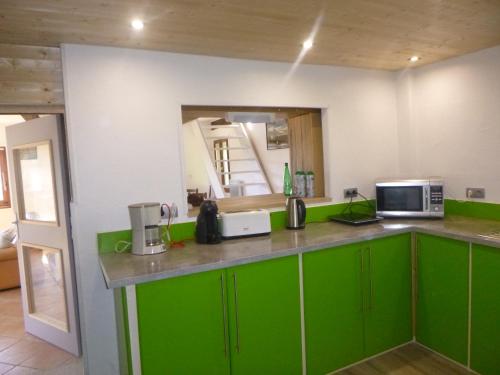 a kitchen with green cabinets and a microwave at La Miellerie des Nuages in Prads-Haute-Bléone
