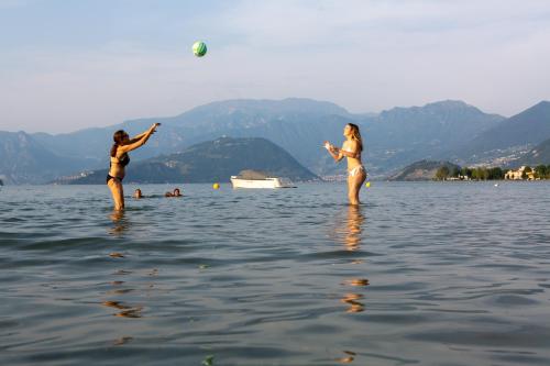 two women playing with a ball in the water at Camping Del Sole Village in Iseo