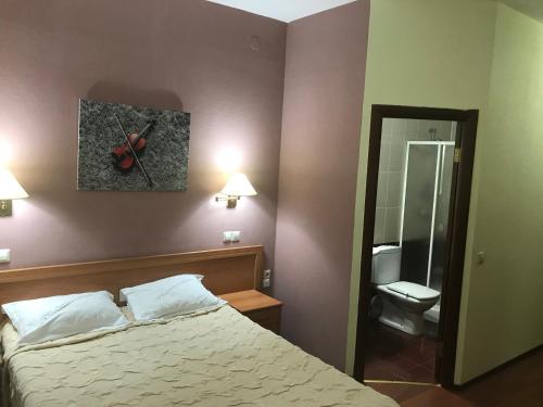 a bedroom with a bed and a bathroom with a toilet at Green Hotel in Atyrau