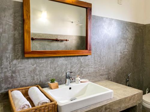 een badkamer met een witte wastafel en een spiegel bij Hanthana House in Kandy