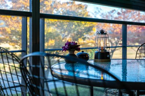 スンチョンにあるFour Seasons Pensionの窓にランプと花を飾ったガラステーブル