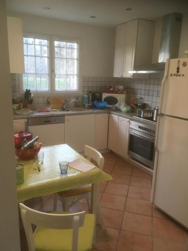 une cuisine avec une table et un réfrigérateur dans l'établissement La maison d'été de mes parents, à Vendays-Montalivet