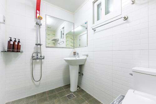 a white bathroom with a sink and a shower at Four Seasons Pension in Suncheon