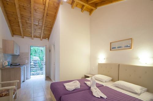 a bedroom with a purple bed and a kitchen at VOULA STUDIOS in Skiathos