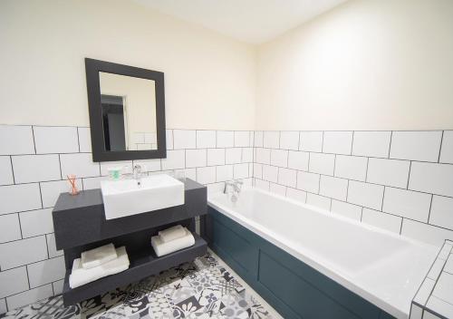 a bathroom with a sink and a tub and a mirror at Heacham Manor Hotel in Hunstanton