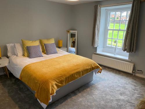 a bedroom with a large bed with a yellow blanket at Listed sword makers cottage in Shotley Bridge in Consett