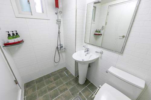 a bathroom with a sink and a toilet and a mirror at Four Seasons Pension in Suncheon