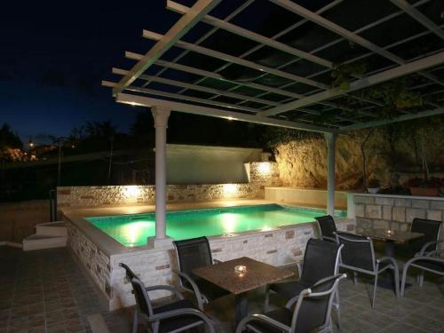 a swimming pool at night with chairs and a table at Kusalo Guesthouse in Dubrovnik