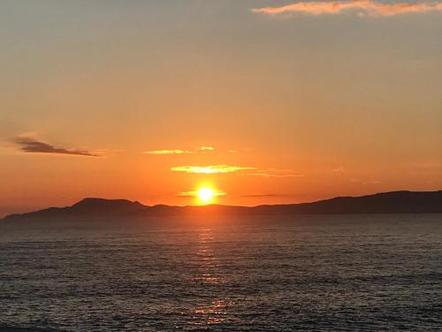 a sunset over the ocean with mountains in the background at The Snuggly Sheep Shepherd Hut Campview Farm Stay in Ballyshannon