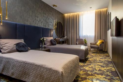 una habitación de hotel con 2 camas y una silla en Hotel Atrium en Cracovia