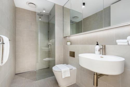 een badkamer met een wastafel, een toilet en een spiegel bij The Surry Apartments by Urban Rest in Sydney