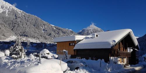 a building covered in snow with mountains in the background at Haus Idili in Sankt Gallenkirch