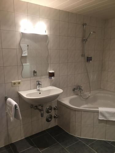 bagno con lavandino, vasca e specchio di Ferienwohnung Thöny Vandans a Vandans