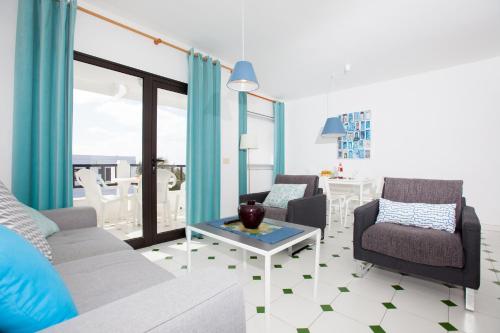 Una sala de estar con un sofá y sillas y una mesa. en Costa Luz 5 Trioblancos, en Tías