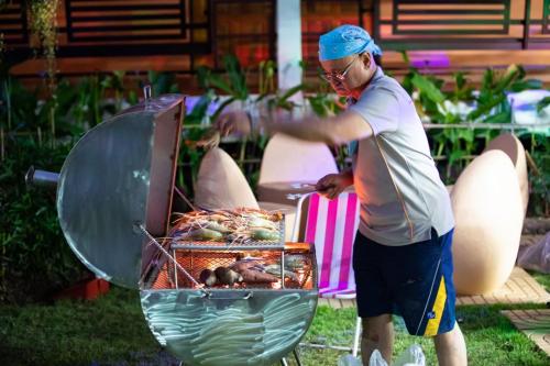 a man is cooking food in a grill at บ้านเขาค้อริมธาร in Ban Non Na Yao