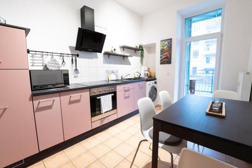eine Küche mit rosa Schränken und einem Tisch mit Stühlen in der Unterkunft Erdgeschoss auf dem gemütlichen Kaßberg in Chemnitz