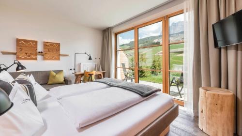a bedroom with two beds and a large window at Miraval NaturHotel in Badia
