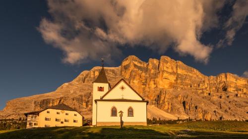 a church on a hill in front of a mountain at Miraval NaturHotel in Badia