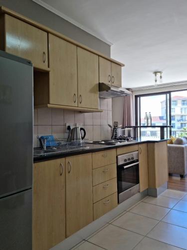 a kitchen with wooden cabinets and a stainless steel refrigerator at Island Club by Smart City Stays in Cape Town