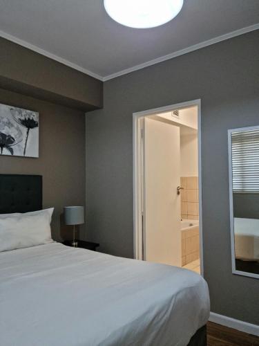 a bedroom with a large bed and a bathroom at Island Club by Smart City Stays in Cape Town