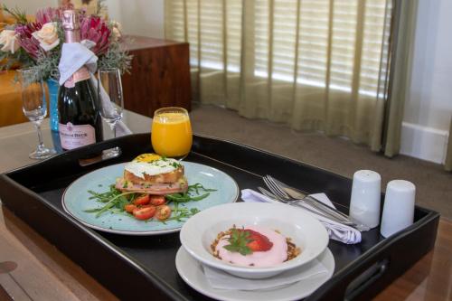 a tray with a plate of food and a glass of orange juice at MyPond Stenden Hotel in Port Alfred