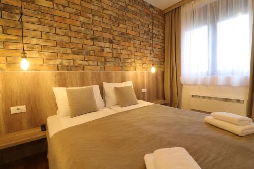 a bedroom with a large bed with a brick wall at All Seasons Residence in Zlatibor