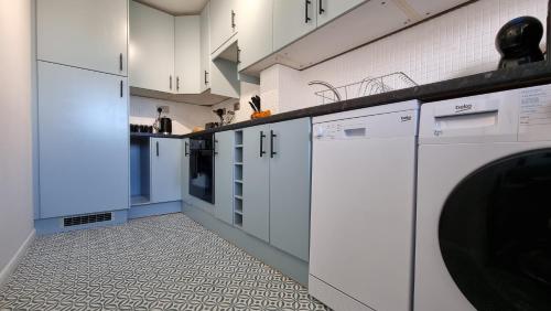 a kitchen with white cabinets and a dishwasher at Haxby House by Switchback Stays in Cardiff