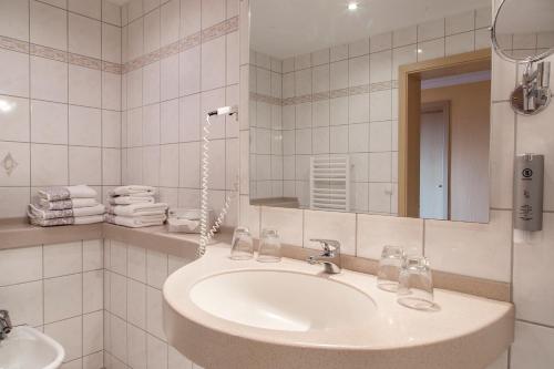 a white bathroom with a sink and a mirror at Hotel Kammweg in Grossbreitenbach