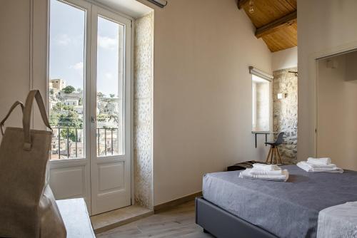 ein Schlafzimmer mit einem Bett und einem großen Fenster in der Unterkunft Casa Teresa con vista sul centro storico by Wonderful Italy in Modica