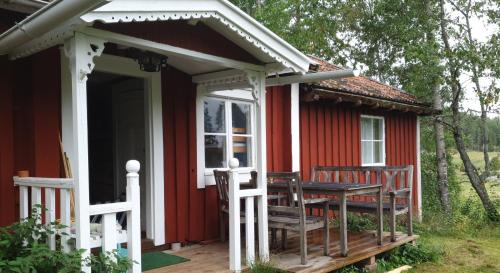 ein rotes Cottage mit einem Tisch und Stühlen auf der Veranda in der Unterkunft Schwedentraum Varpstugan in Kisa