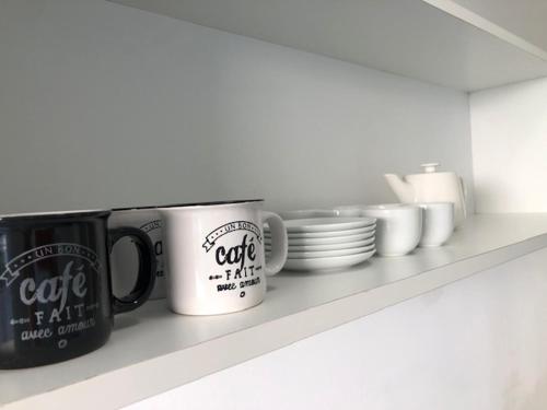 une étagère avec des tasses à café et des assiettes dessus dans l'établissement Seaspray 1 Bedroom, Monaco, Sea View, à Beausoleil