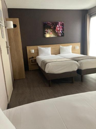 a bedroom with two beds and a painting on the wall at Hotel Wood Inn Bordeaux Aéroport in Mérignac