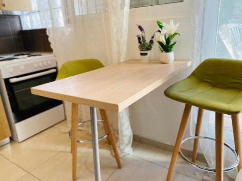 une cuisine avec une table en bois et deux chaises vertes dans l'établissement Cozy apartment near sea, à Athènes