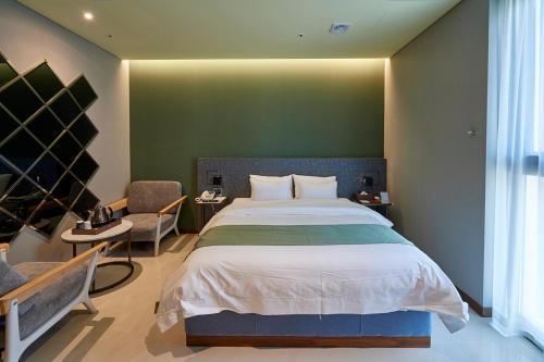 a bedroom with a large bed and a green wall at Gimpo Stavia in Gimpo