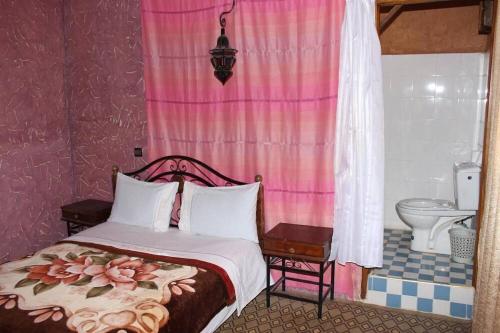 1 dormitorio con 1 cama y baño con aseo en Auberge et hôtel les amis tafraout, en Tafraoute