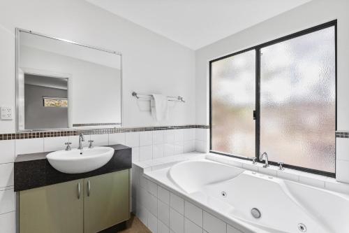 La salle de bains blanche est pourvue d'une baignoire et d'un lavabo. dans l'établissement Beachside at Margaret River - Spacious Family Beach House in Exclusive Prevelly Location, à Prevelly